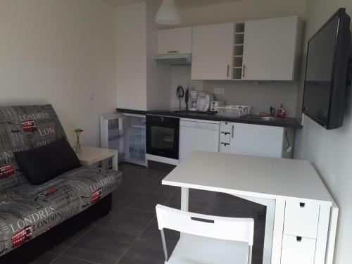 Il comprend un salon avec une table blanche et une cuisine. dans l'établissement le cube cassiopée, au Cap d'Agde