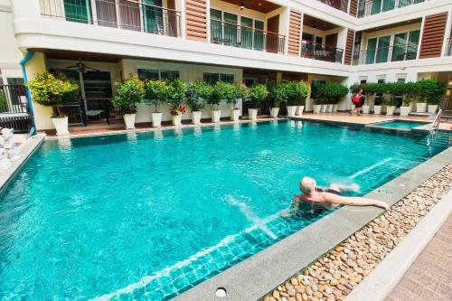 a man laying in a swimming pool in a hotel at The Paradise Jomtien Beach in Jomtien Beach
