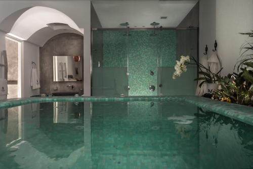 a bathroom with a large swimming pool in a room at Elements of Caldera Suites in Akrotiri