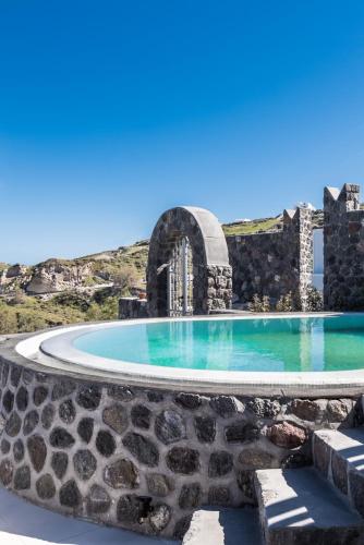 a swimming pool with a stone wall around it at Elements of Caldera Suites in Akrotiri