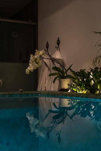 a person standing next to a swimming pool with flowers at Elements of Caldera Suites in Akrotiri