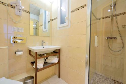 a bathroom with a sink and a shower at Hotel Capitole in Beausoleil