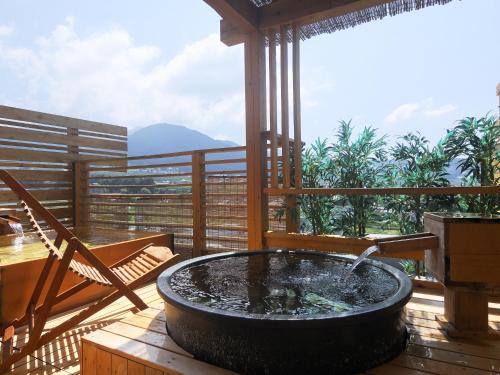 a hot tub on a deck with a table and chairs at Hotel Tsubakino in Yamanouchi