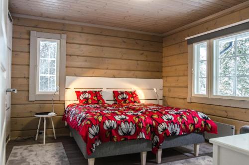 a bedroom with a bed with a red comforter and two windows at Villa Avanto in Suomenniemi