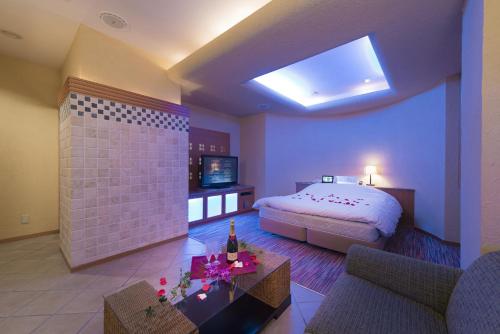 a bedroom with a bed and a couch and a table at Hotel Chateau Briant (Adult only) in Saitama