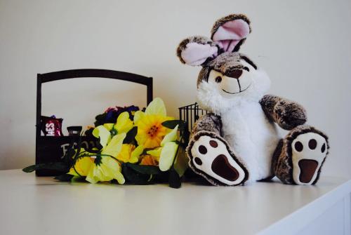 a stuffed rabbit sitting on a shelf next to flowers at Vakantiestudio Melroce in Bredene