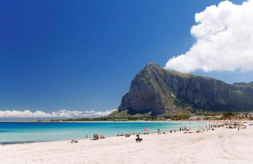 a group of people on a beach with a mountain in the background at Baglio La Porta by Geocharme in San Vito lo Capo