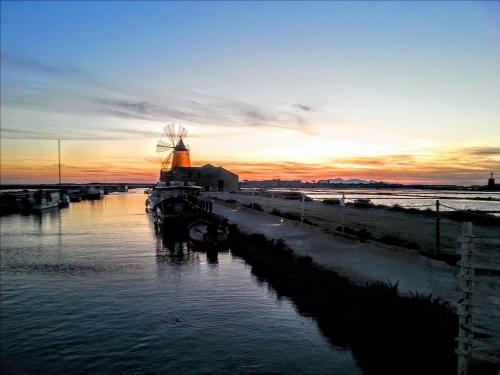 a sunset over a river with a windmill at B&B MaryJosè in Trapani