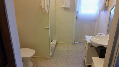 a bathroom with a toilet and a sink and a shower at Herons Reef Holiday Apartments in Rarotonga