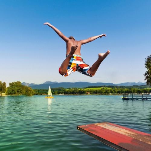 a man jumping off a dock into a lake at Ferienwohnung Schmuckkastl in Tittmoning
