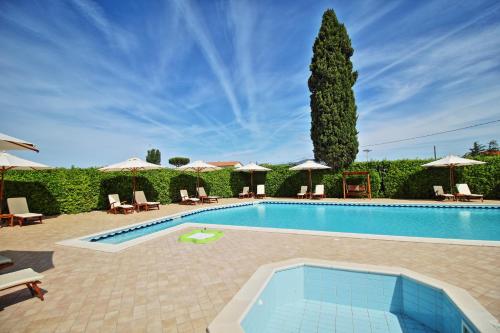 una piscina con sillas, sombrillas y un árbol en Podere Tre Cipressi Country Resort, en Campiglia Marittima