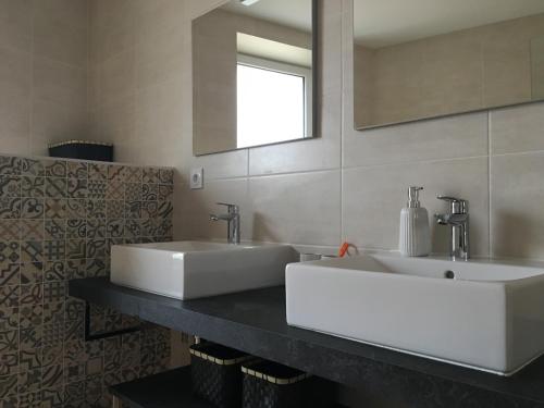 a bathroom with two white sinks and a mirror at La Maison du Bonheur - Grande maison de vacances classée 4 étoiles in Le Boupère