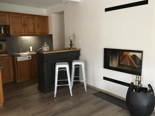 a kitchen with two stools next to a counter at La Maison du Bonheur - Grande maison de vacances classée 4 étoiles in Le Boupère