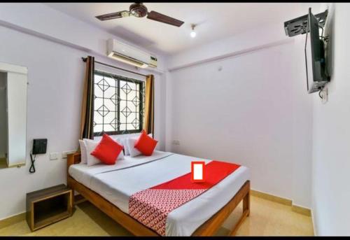 una camera da letto con un letto con cuscini rossi e una TV di Sweet AC Rooms near KFC Restaurant a Saligao
