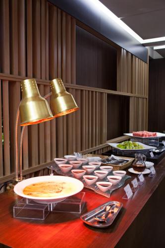ein Buffet mit Speisen auf einem Tisch mit einer Glocke in der Unterkunft Beitou Sweet Me Hot Spring Resort in Taipeh