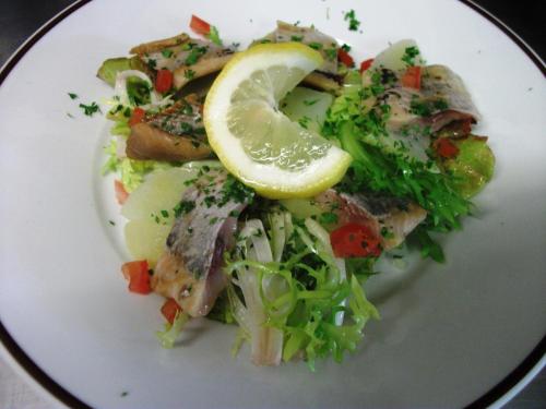 a plate of food with a salad and a lemon wedge at Logis hôtel Au Relais Nivernais in Nevers