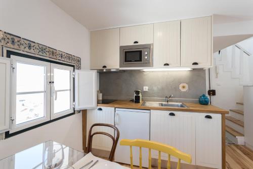 a kitchen with white cabinets and a sink and a window at Alfama Loft Studio Loft Apartment w/ River View - by LU Holidays in Lisbon