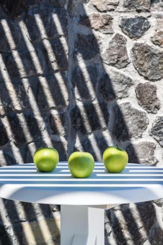 three apples are sitting on a white bench with shadows at Elements of Caldera Suites in Akrotiri