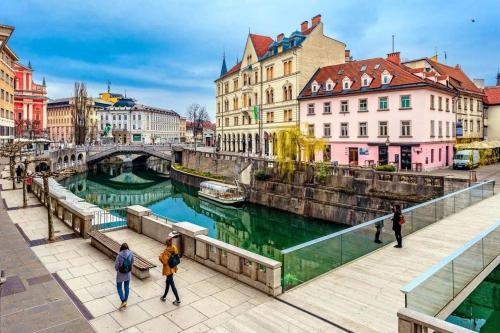 a group of people walking on a bridge over a river at Hotel Slamič Ljubljana in Ljubljana