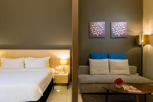 a hotel room with a bed and a couch at The Pines Melaka in Melaka