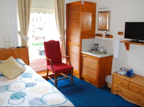a bedroom with a bed and a chair and a window at Denmore Guest House in Aberdeen