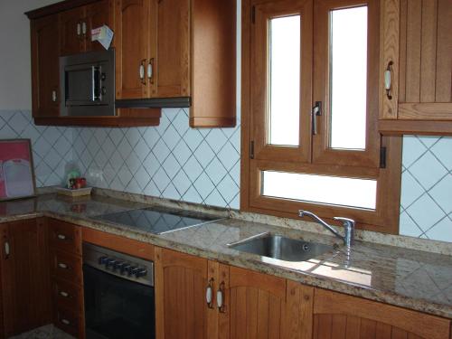 una cucina con armadi in legno e lavandino di CARABEO 70 MENYBER a Nerja