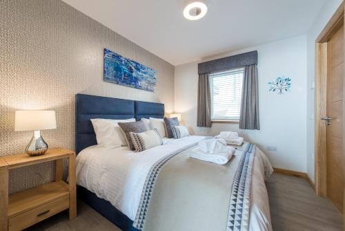 a bedroom with a large bed with a blue headboard at Dalriada Lodges Strathlethan in Stonehaven