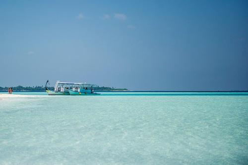 a boat sitting on the shore of a beach at Detour Beach View in Hangnaameedhoo