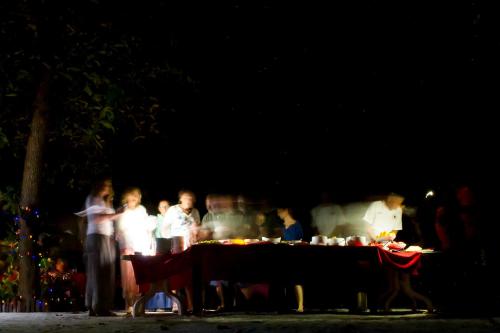 a group of people standing around a table at night at Detour Beach View in Hangnaameedhoo