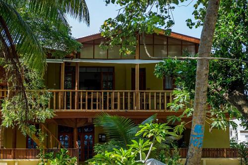 a green house with a balcony and trees at Detour Beach View in Hangnaameedhoo