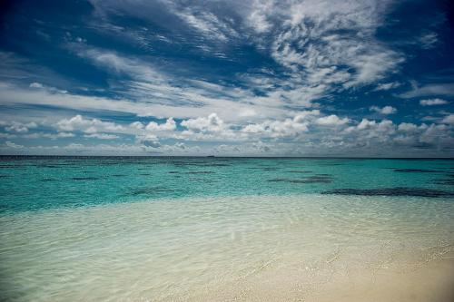 a beach with blue water and a cloudy sky at Detour Beach View in Hangnaameedhoo