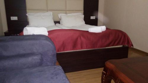a bed with two pillows and a couch in a room at Hotel White Neptun Georgia Tbilisi in Tbilisi City