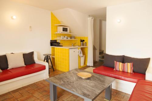 a living room with two couches and a table and a kitchen at Hotel Vasco Da Gama in Monte Gordo