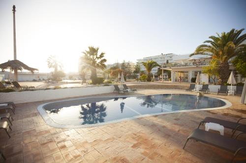 a large swimming pool in a resort with palm trees at Hotel Vasco Da Gama in Monte Gordo