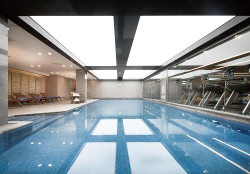 a swimming pool with chairs in a building at Fraser Place Central Seoul in Seoul