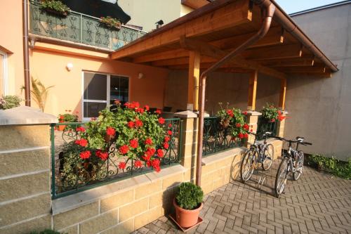 a bicycle parked under a balcony with red flowers at H+M Penzion in Brno