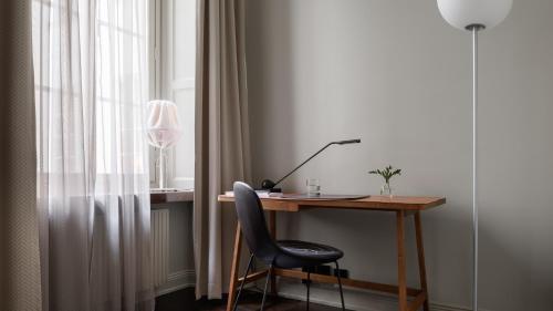 a desk with a lamp on top of it next to a window at Nobis Hotel Stockholm, a Member of Design Hotels™ in Stockholm