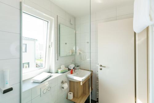 La salle de bains blanche est pourvue d'un lavabo et d'un miroir. dans l'établissement Come IN Comfort, à Ingolstadt
