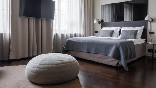 a bedroom with a bed with a ottoman in front of it at Nobis Hotel Stockholm, a Member of Design Hotels™ in Stockholm