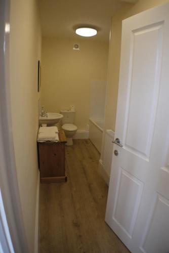 a bathroom with a toilet and a sink and a door at Oliver Cromwell Hotel in March