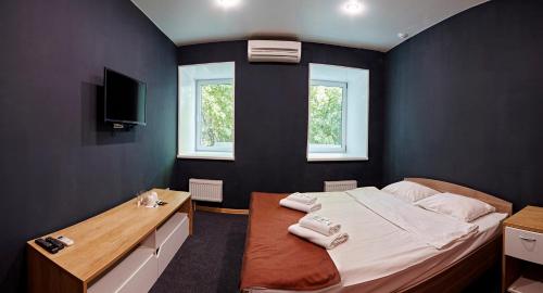 a bedroom with a bed and a desk and two windows at Baget Hotel in Nizhny Novgorod