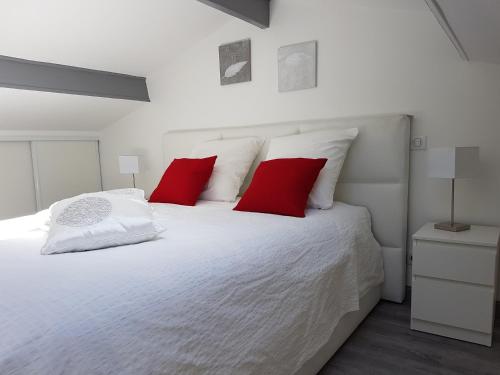 um quarto com uma cama branca e almofadas vermelhas em Mikado em La Gaude
