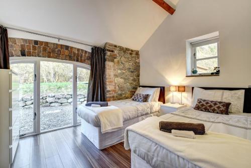 a bedroom with two beds and a stone wall at Beudy Menai in Llanddeiniolen