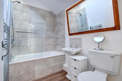 a bathroom with a toilet and a tub and a sink at Beudy Menai in Llanddeiniolen