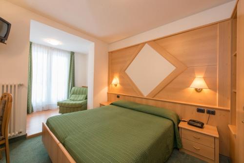 a bedroom with a green bed with a wooden headboard at Hotel Italia in Castello di Fiemme