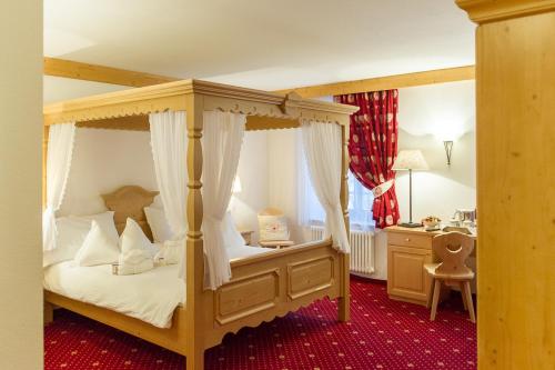 a bedroom with a canopy bed and a desk at Hotel Italia in Castello di Fiemme