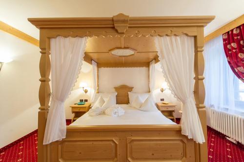 a bedroom with a canopy bed with white curtains at Hotel Italia in Castello di Fiemme
