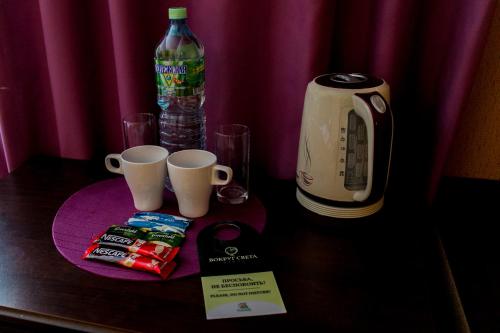 uma mesa com duas chávenas de café e uma garrafa de água em Vokrug Sveta Dubna Hotel em Dubna