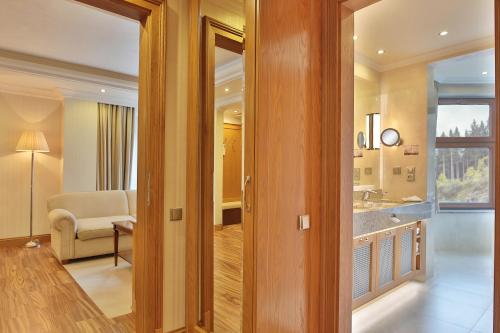 a room with a bathroom with a sink and a living room at Retro Riverside Wellness Resort in Karlovy Vary