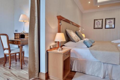 a bedroom with a bed and a desk with a lamp at Retro Riverside Wellness Resort in Karlovy Vary